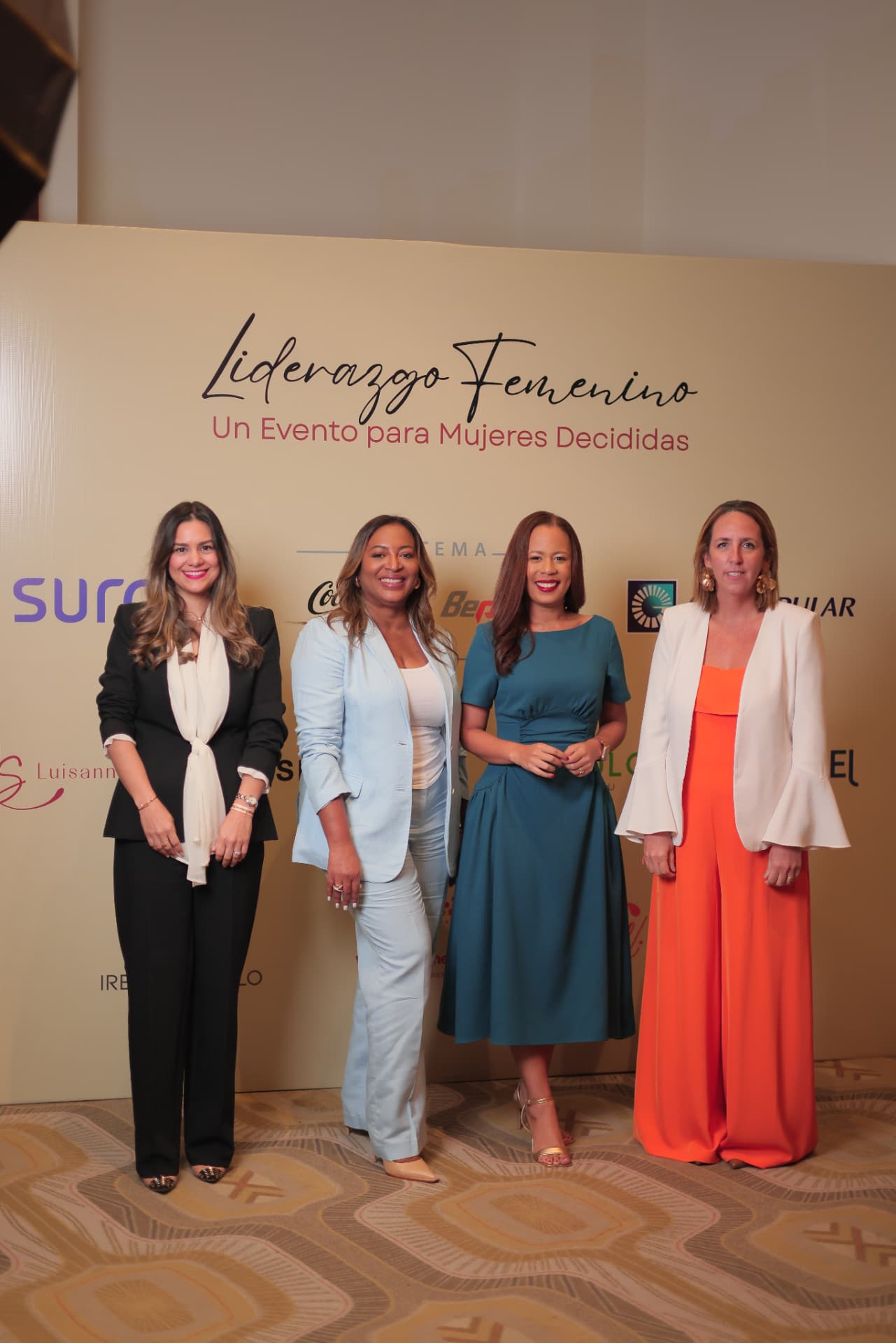 Equipo organizador de Liderazgo Femenino frente al backdrop del evento